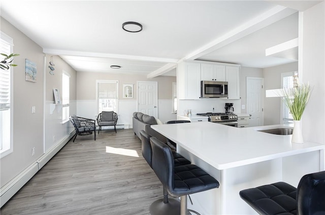 kitchen with a kitchen bar, appliances with stainless steel finishes, kitchen peninsula, and white cabinetry