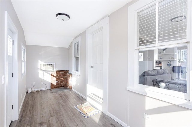 hallway featuring hardwood / wood-style floors, lofted ceiling, and an AC wall unit