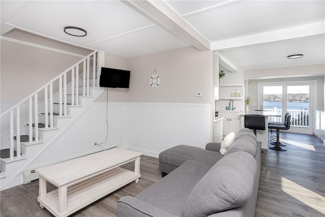 living room featuring beamed ceiling, wood-type flooring, baseboard heating, and sink