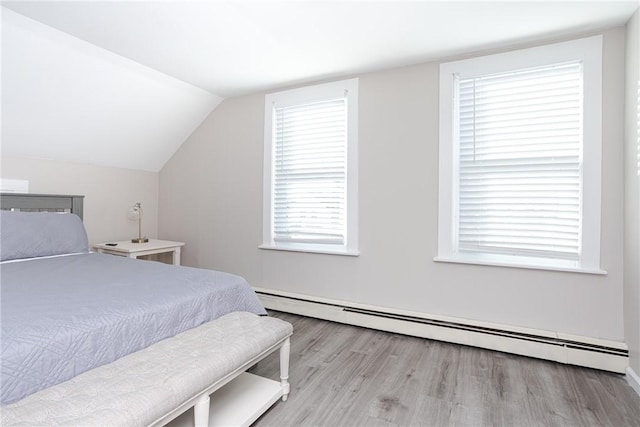 bedroom with light hardwood / wood-style flooring, baseboard heating, and lofted ceiling