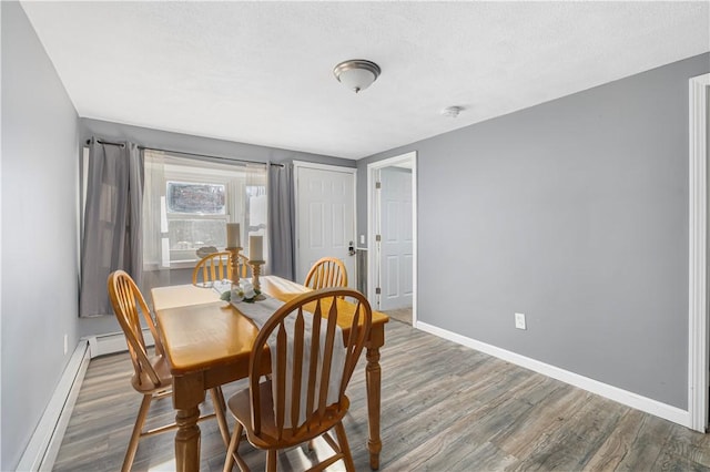 dining room with dark hardwood / wood-style flooring, a baseboard radiator, and a textured ceiling