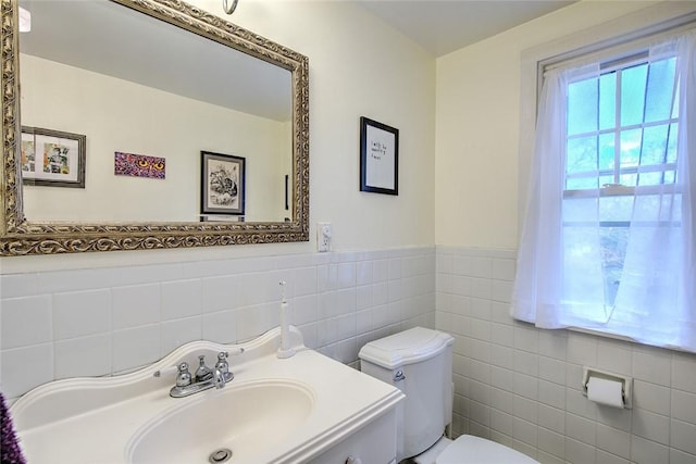 bathroom featuring sink, tile walls, and toilet