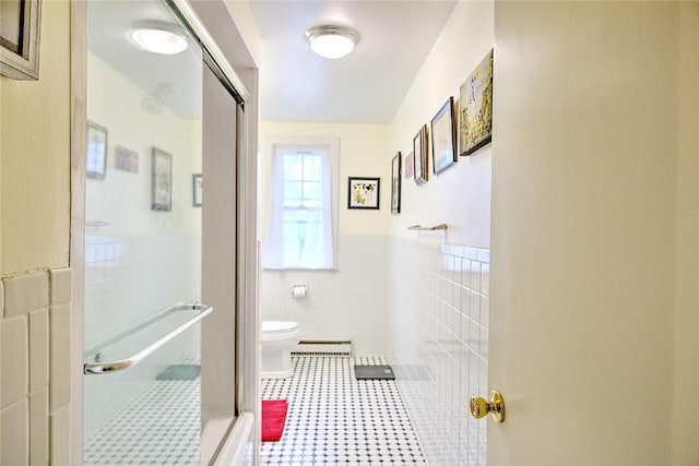 bathroom featuring tile patterned flooring, an enclosed shower, tile walls, and toilet