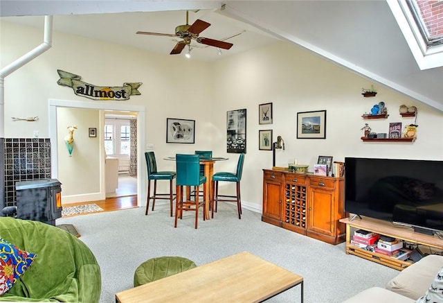 carpeted living room featuring ceiling fan, a wood stove, and vaulted ceiling