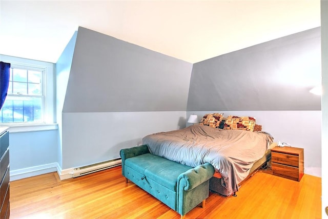 bedroom with hardwood / wood-style floors and a baseboard heating unit