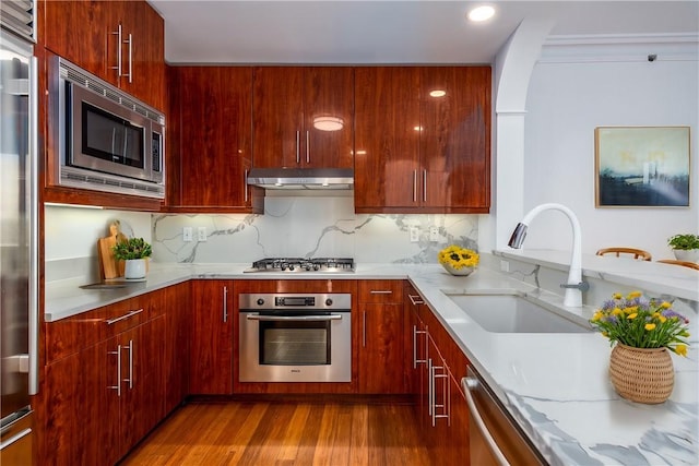 kitchen with hardwood / wood-style flooring, stainless steel appliances, sink, and decorative backsplash