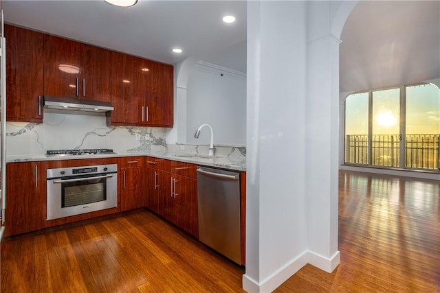 kitchen with appliances with stainless steel finishes, dark hardwood / wood-style floors, tasteful backsplash, sink, and crown molding