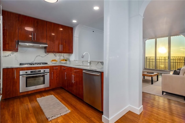 kitchen featuring appliances with stainless steel finishes, wood-type flooring, sink, and decorative backsplash