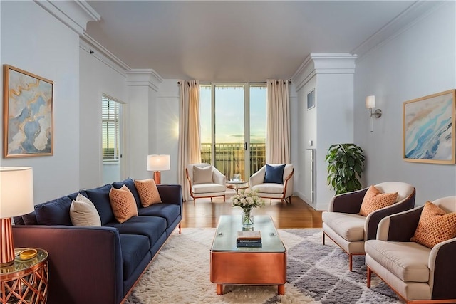 living room with crown molding, a wall of windows, light hardwood / wood-style floors, and decorative columns