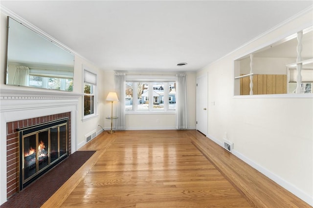 unfurnished living room featuring a fireplace, wood-type flooring, and crown molding