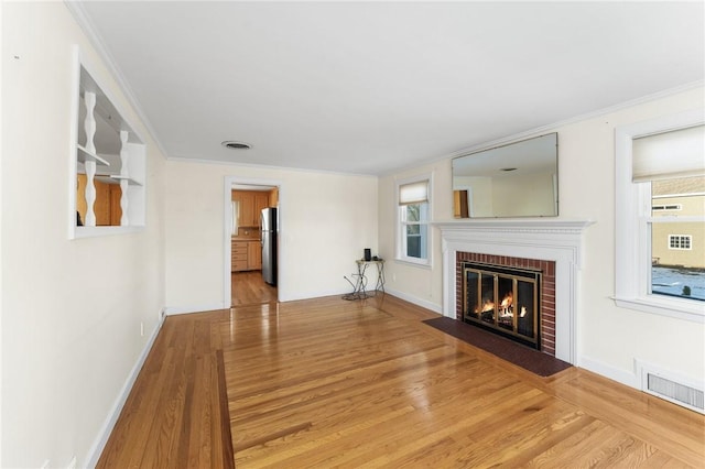 unfurnished living room with crown molding, light hardwood / wood-style flooring, and a brick fireplace