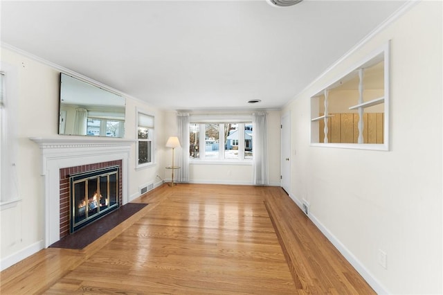 unfurnished living room with a fireplace, light wood-type flooring, and ornamental molding