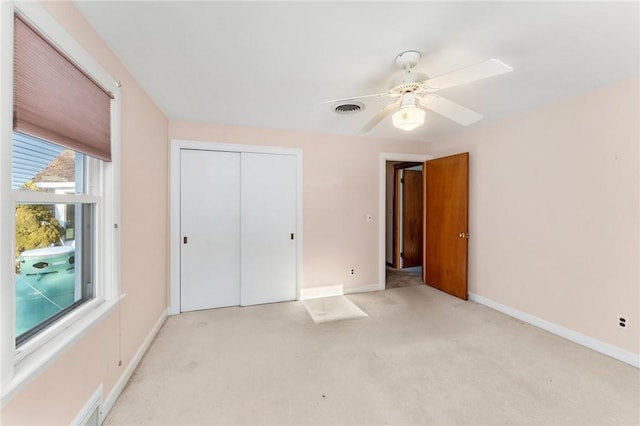 unfurnished bedroom with ceiling fan, light carpet, and a closet