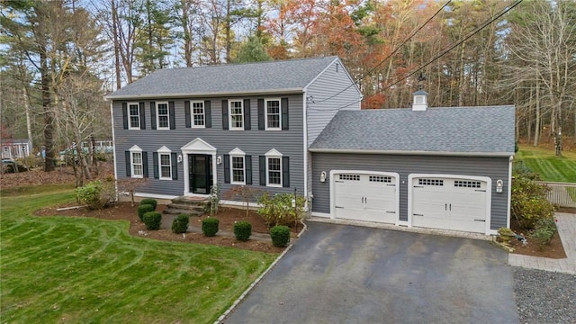 colonial inspired home with a garage and a front yard