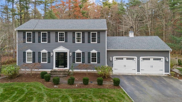 colonial home with a garage and a front lawn