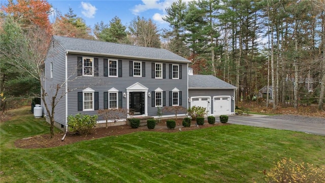 colonial house featuring a garage and a front lawn