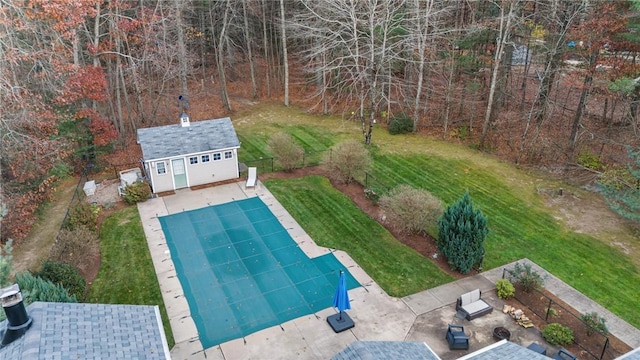 view of swimming pool featuring a lawn, a patio area, and a storage unit