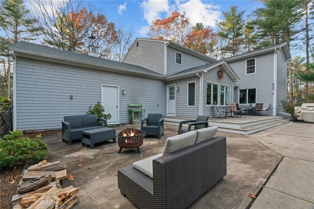 back of house with a patio area and an outdoor living space with a fire pit