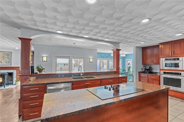 kitchen featuring sink, light tile patterned floors, appliances with stainless steel finishes, decorative columns, and a kitchen island