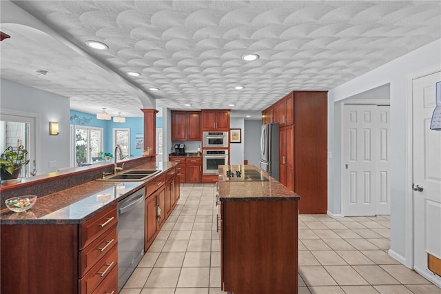 kitchen with light tile patterned flooring, appliances with stainless steel finishes, sink, and a kitchen island