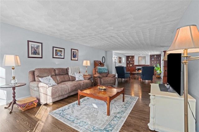 living room with dark hardwood / wood-style floors, a textured ceiling, and built in shelves