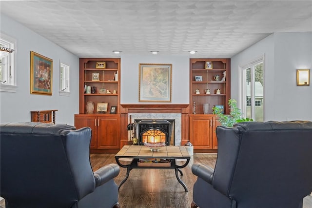 living room with built in shelves, a high end fireplace, a textured ceiling, and hardwood / wood-style flooring