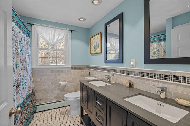 bathroom with a baseboard radiator, vanity, toilet, and tile walls