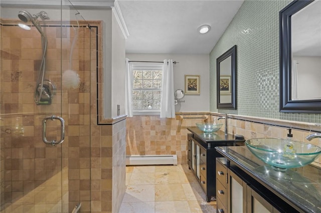 bathroom featuring tile walls, a baseboard radiator, vanity, ornamental molding, and a shower with door