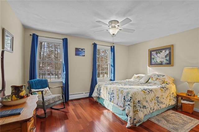 bedroom with ceiling fan, dark hardwood / wood-style flooring, multiple windows, and a baseboard heating unit