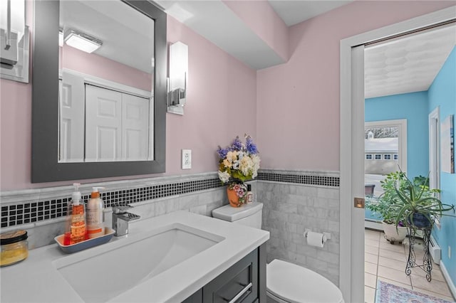 bathroom with tile walls, vanity, tile patterned floors, and toilet