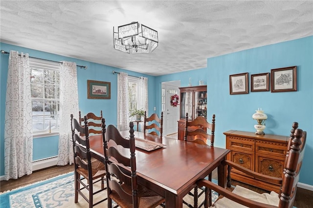 dining space featuring wood-type flooring, a textured ceiling, a chandelier, and a baseboard radiator