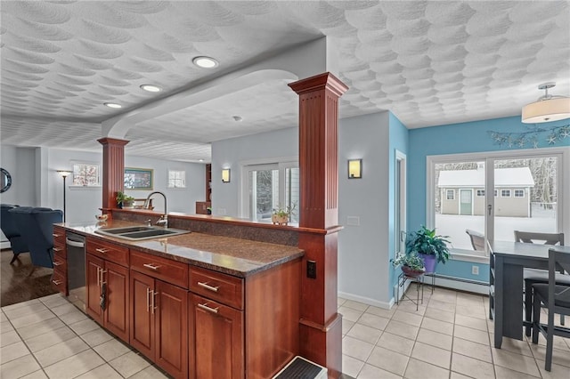 kitchen with sink, decorative columns, a wealth of natural light, a baseboard radiator, and stainless steel dishwasher