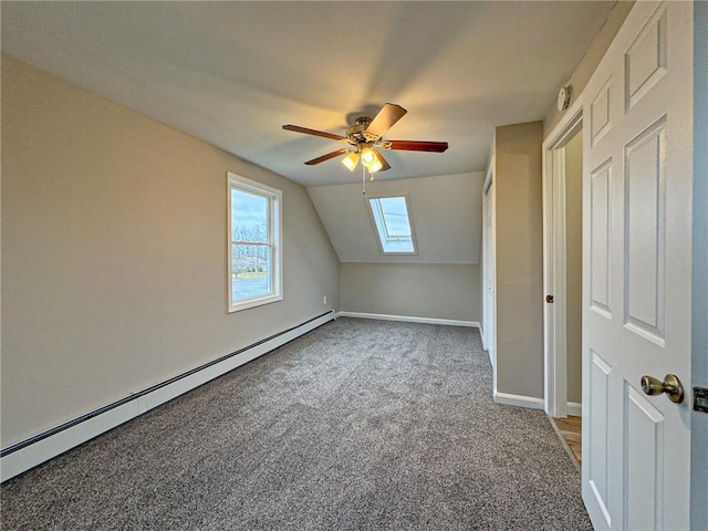 additional living space featuring carpet flooring, a baseboard radiator, lofted ceiling with skylight, and ceiling fan