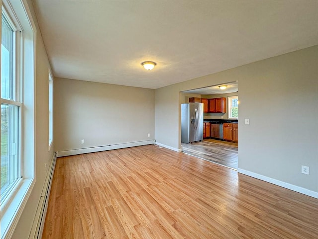 unfurnished living room with baseboard heating and light hardwood / wood-style floors