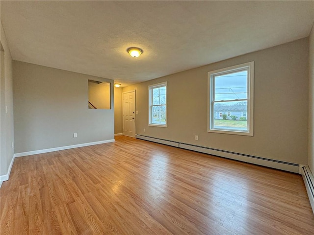 unfurnished room featuring light wood-type flooring, a textured ceiling, and a baseboard heating unit