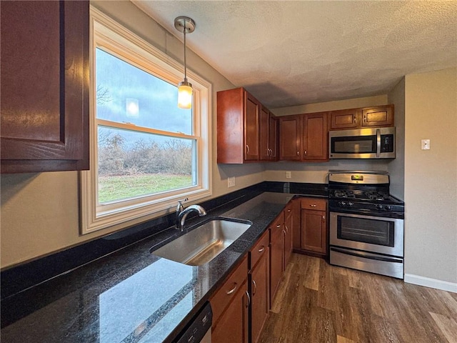 kitchen with appliances with stainless steel finishes, a textured ceiling, sink, decorative light fixtures, and dark hardwood / wood-style floors