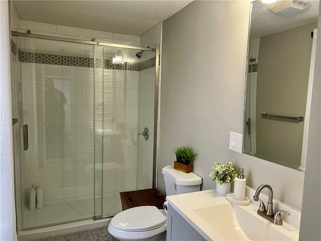 bathroom with a textured ceiling, vanity, an enclosed shower, and toilet