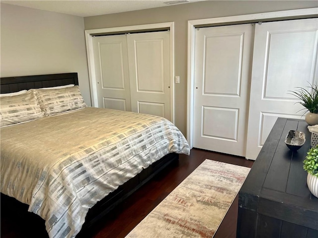 bedroom with multiple closets and dark hardwood / wood-style flooring