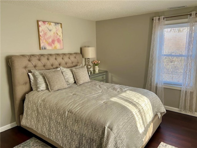 bedroom with a textured ceiling and dark wood-type flooring