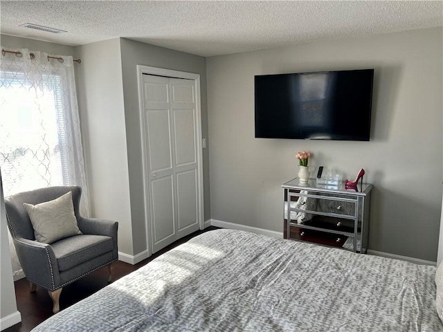 bedroom featuring dark hardwood / wood-style floors, a textured ceiling, and a closet