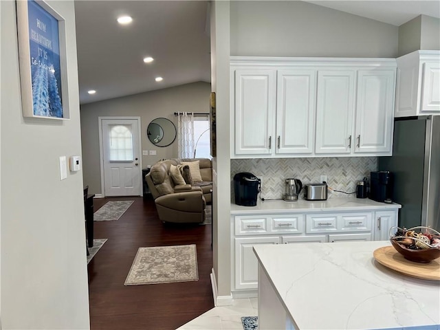 kitchen with decorative backsplash, white cabinetry, light stone countertops, and lofted ceiling