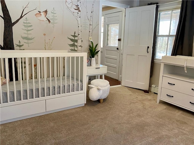 bedroom featuring a crib, baseboard heating, and light carpet