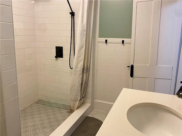 bathroom with sink, tile patterned flooring, tile walls, and walk in shower