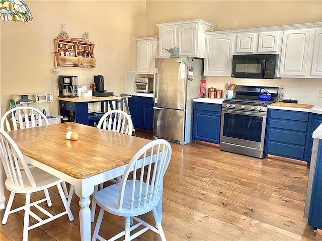 kitchen with blue cabinetry, tasteful backsplash, light hardwood / wood-style flooring, white cabinets, and appliances with stainless steel finishes