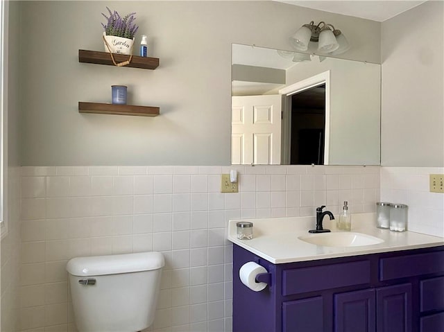 bathroom with vanity, toilet, and tile walls