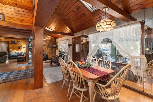 dining space featuring beam ceiling, wood walls, light hardwood / wood-style flooring, and high vaulted ceiling