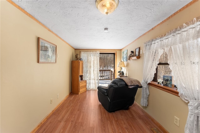 living area featuring wood-type flooring, a textured ceiling, and ornamental molding