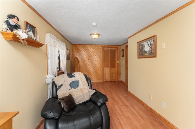 sitting room featuring light hardwood / wood-style floors, a textured ceiling, and ornamental molding