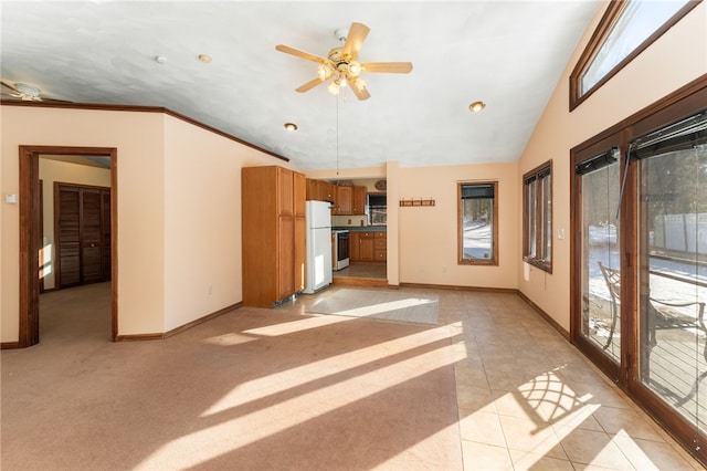 unfurnished living room featuring vaulted ceiling, a wealth of natural light, ceiling fan, and light tile patterned floors