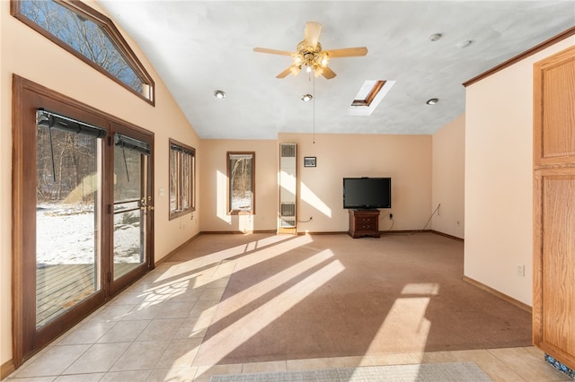 unfurnished living room featuring vaulted ceiling with skylight, ceiling fan, and light tile patterned floors